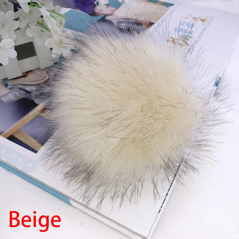 Pompon en fausse fourrure beige, accessoire pour les cheveux, exposé sur un livre.