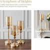 Three brass pillar candle holders of varying heights displayed on a dark wooden surface.