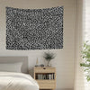 A black and white leopard print decorative wall tapestry hanging on a light-colored wall.