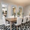 A dining room features a wooden table surrounded by chairs and three tall silver crystal rhinestone wall mirrors.
