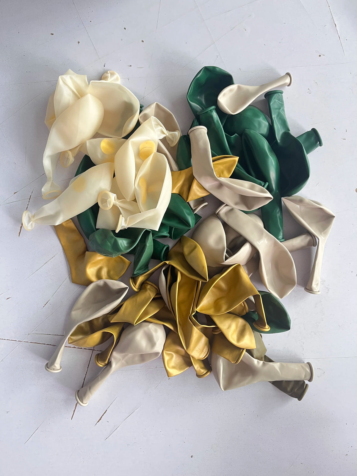 A collection of sage green and gold confetti balloons in various shapes and sizes.