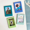Three magnetic photo frames in shades of blue and green displaying photos of a giraffe, a person, and a sheep.