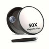 A black magnifying compact mirror with a circular lens and a suction cup is shown on a white background.