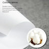 A close-up view of white cotton canvas material with a small piece of dark brown fabric resting on it.