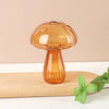 A translucent amber glass vase shaped like a mushroom, resting on a light wooden surface.