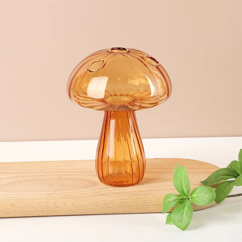 A translucent amber glass vase shaped like a mushroom, resting on a light wooden surface.