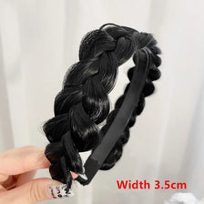 Black braided hair band with a black elastic band shown being held by a hand.