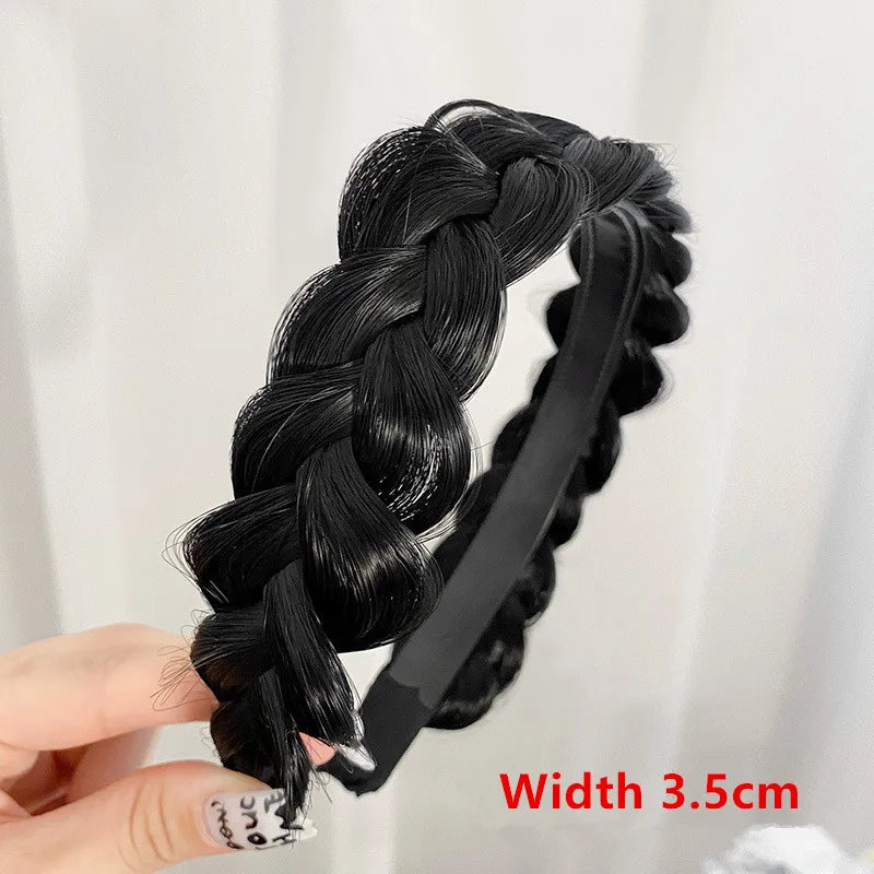 Black braided hair band with a black elastic band shown being held by a hand.