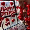 A display of red foil heart-shaped balloons and ribbons for a birthday celebration.