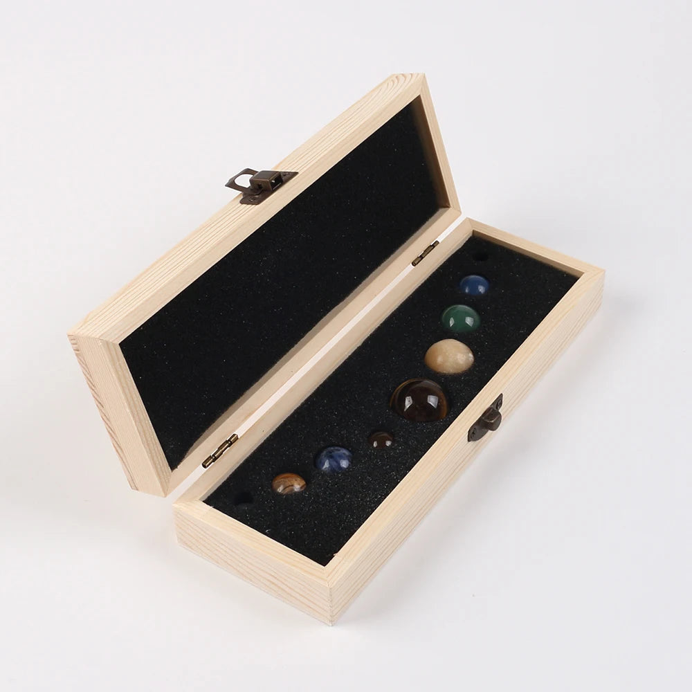 A wooden box with a lid open displaying a set of natural crystal gemstone spheres.