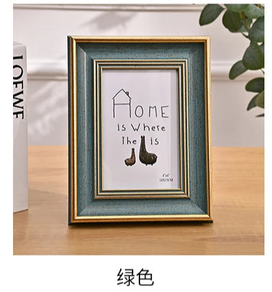 A framed print featuring the text Home is Where the is, displayed in a teal-green wooden frame.