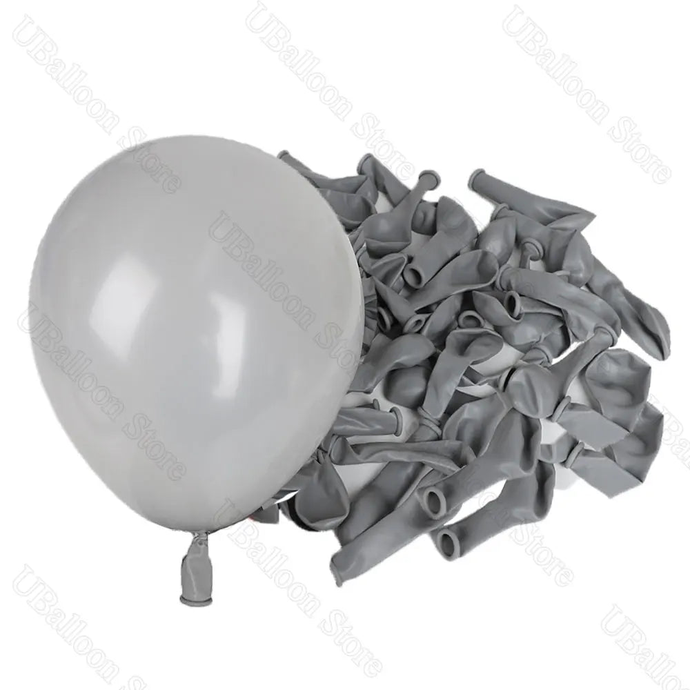 A white latex balloon next to a pile of grey latex balloons for decor.