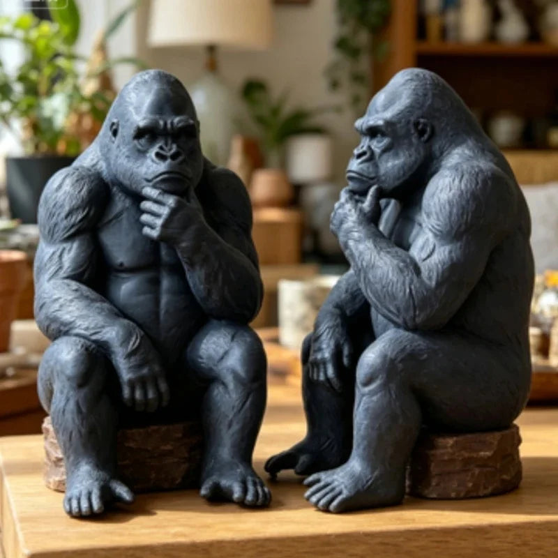 A dark gray 3D-printed gorilla figurine sitting and thinking on a wooden surface.