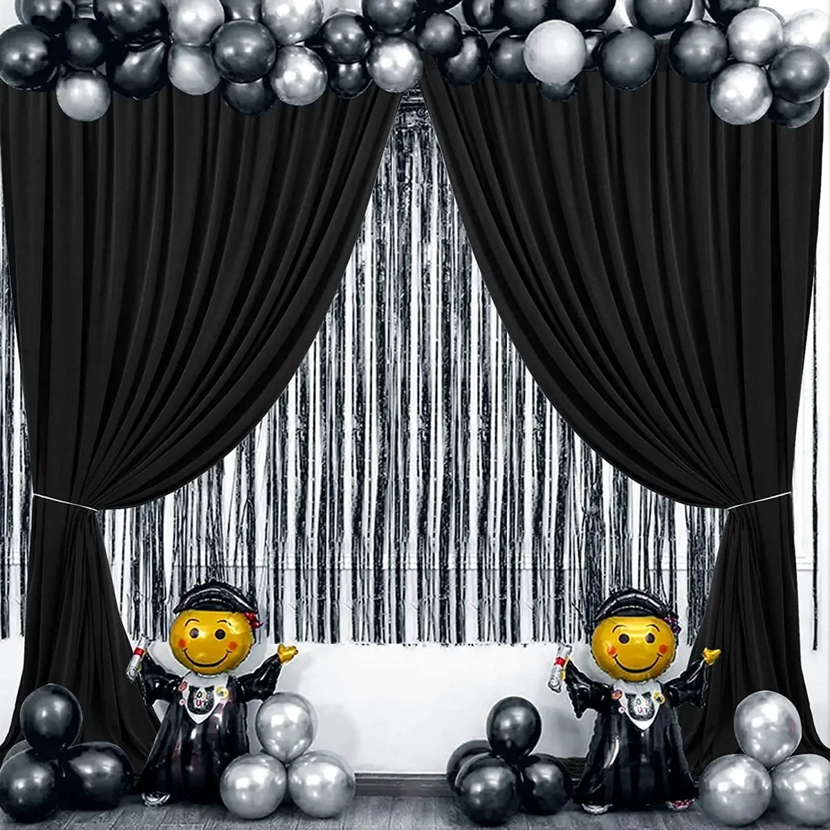 A black and silver draped backdrop curtain with a striped background and balloons.