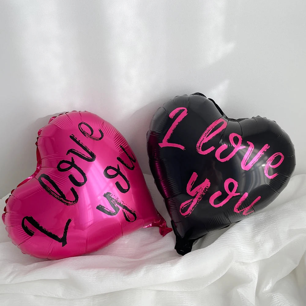 A set of ten black heart-shaped balloons with pink text saying I love you