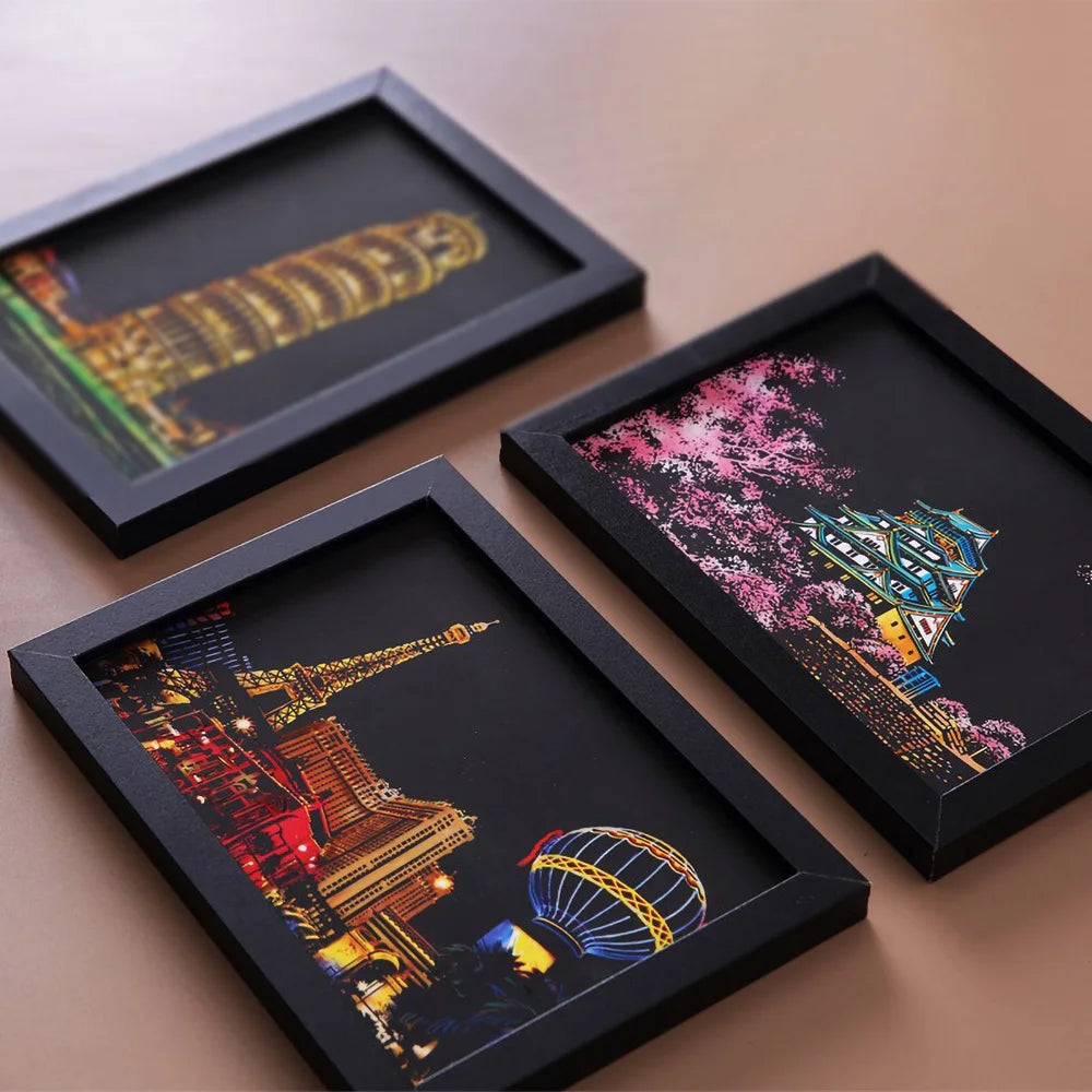 Three framed pieces of art showing cityscapes and fireworks created with scratch painting techniques.