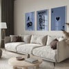 A modern living room features a light sofa and wooden coffee table with framed art prints on the wall.