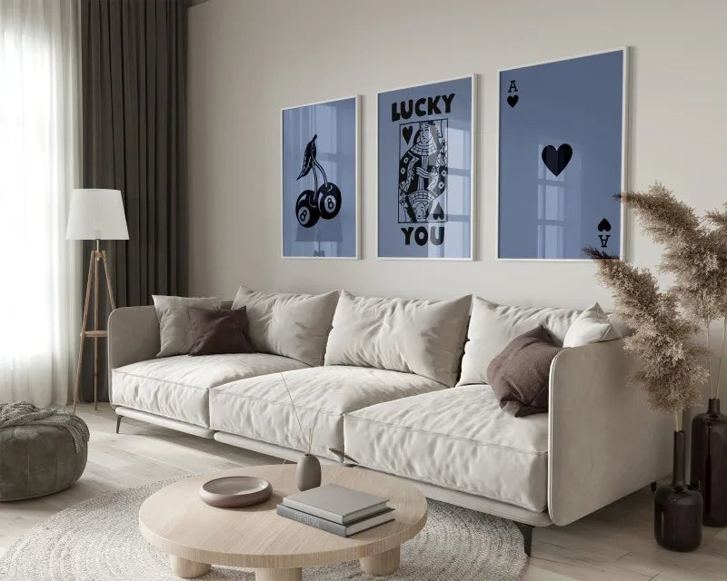 A modern living room features a light sofa and wooden coffee table with framed art prints on the wall.