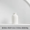 White ceramic tabletop vase with a smooth, rounded shape on a white shelf.