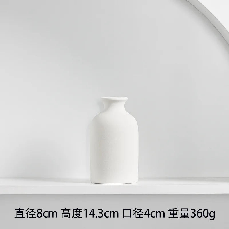 White ceramic tabletop vase with a smooth, rounded shape on a white shelf.