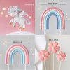 A set of unicorn-themed cake toppers, including a white unicorn figure and rainbow arches in pink and blue.