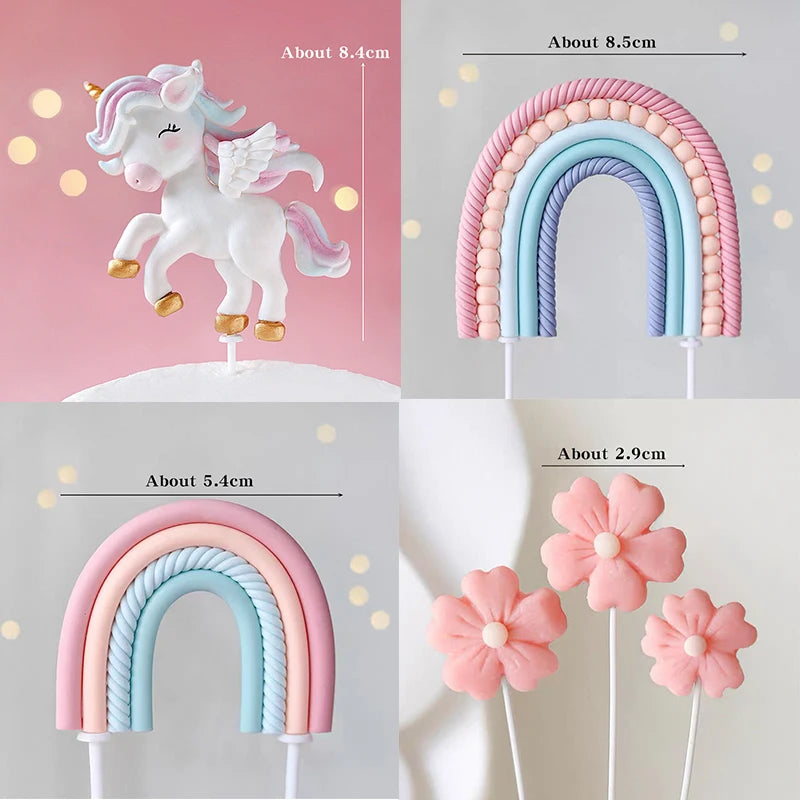 A set of unicorn-themed cake toppers, including a white unicorn figure and rainbow arches in pink and blue.