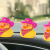 Three yellow rubber duck car dashboard decorations wearing pink cowboy hats on a black car interior.