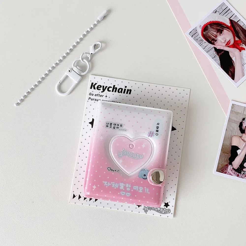 A pink heart-shaped photo album keychain with a clear cover and a silver chain is displayed on a white surface.