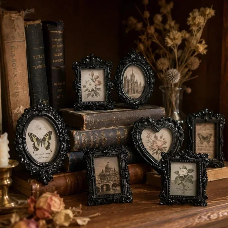 A collection of vintage resin mini picture frames displayed on a wooden surface surrounded by old books and dried floral elem