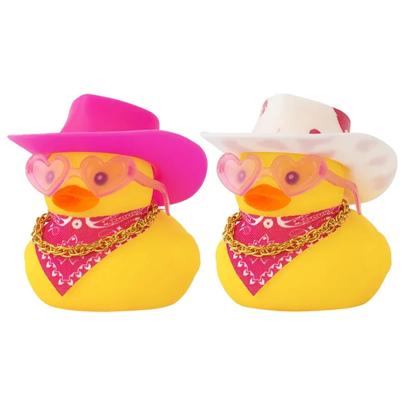 Two yellow rubber duck car dashboard decorations with pink cowboy hats and gold chains