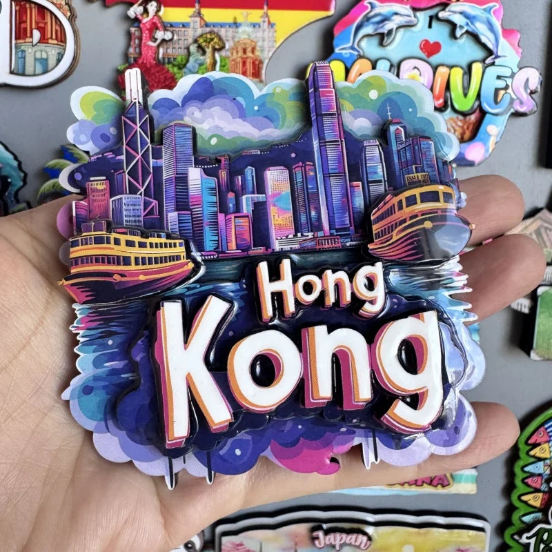 A hand holds a collection of wooden fridge magnets featuring a cityscape and the text Hong Kong.