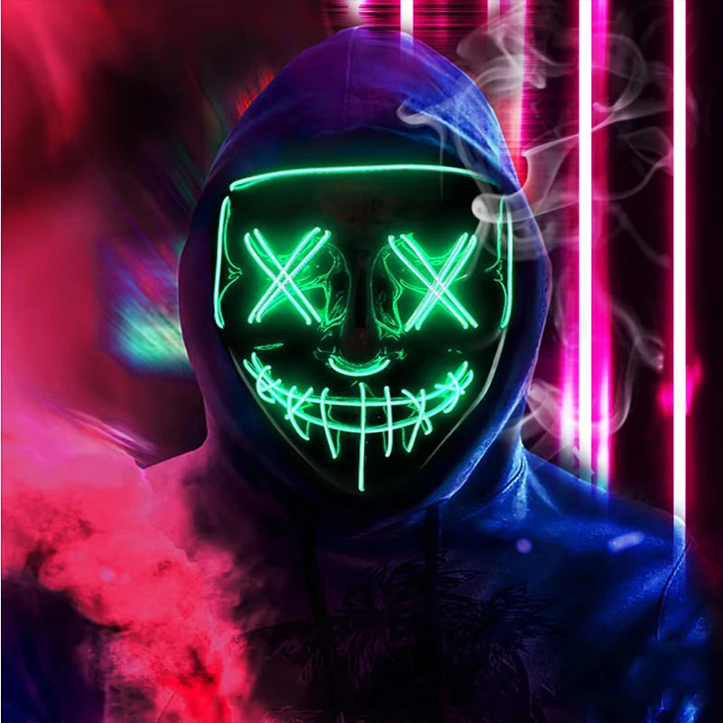 A person wearing a dark hoodie and a glowing green LED mask with an 'X' pattern, set against a background of red and pink lig