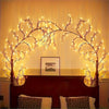 Flexible willow branch LED lights illuminating a framed picture above a dark wooden cabinet.