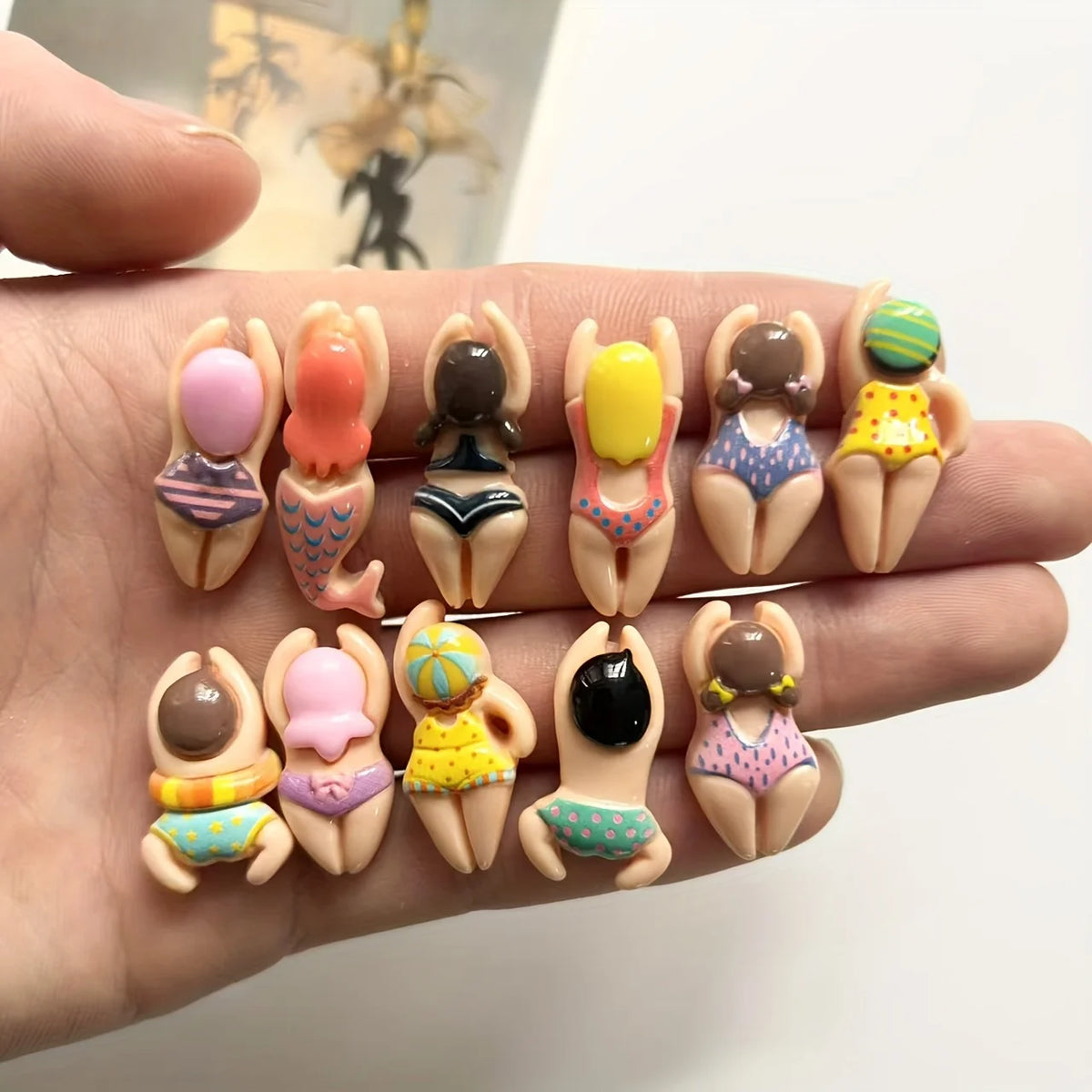 A hand holds a set of six resin fridge magnets featuring various colors and designs.