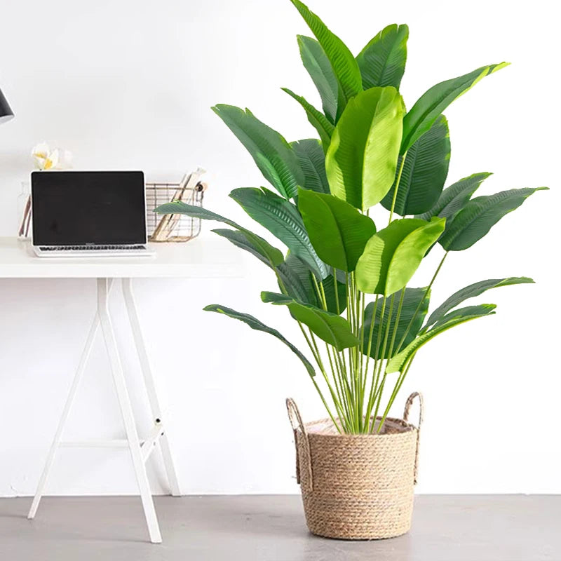 Artificial tropical palm tree with large green monstera leaves potted in a woven basket