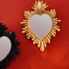 A golden flame sacred heart wall pendant with a resin finish displayed against a red background.