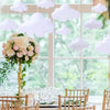 White cloud felt decorations hanging from a window frame in a bright room.