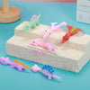 A collection of colorful dinosaur-shaped slingshot flying toys for kids displayed on a white block.