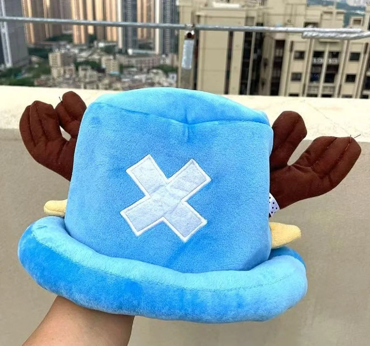 A light blue knit cap plush toy featuring a white 'X' design and brown ears.