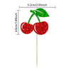 A set of two glittery red cherry and green leaf cake toppers on wooden sticks.