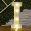 A glowing warm white LED alphabet letter light shaped like the letter I standing on a wooden surface.