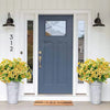 A dark blue door with glass panels flanked by white trim and potted yellow artificial flowers.