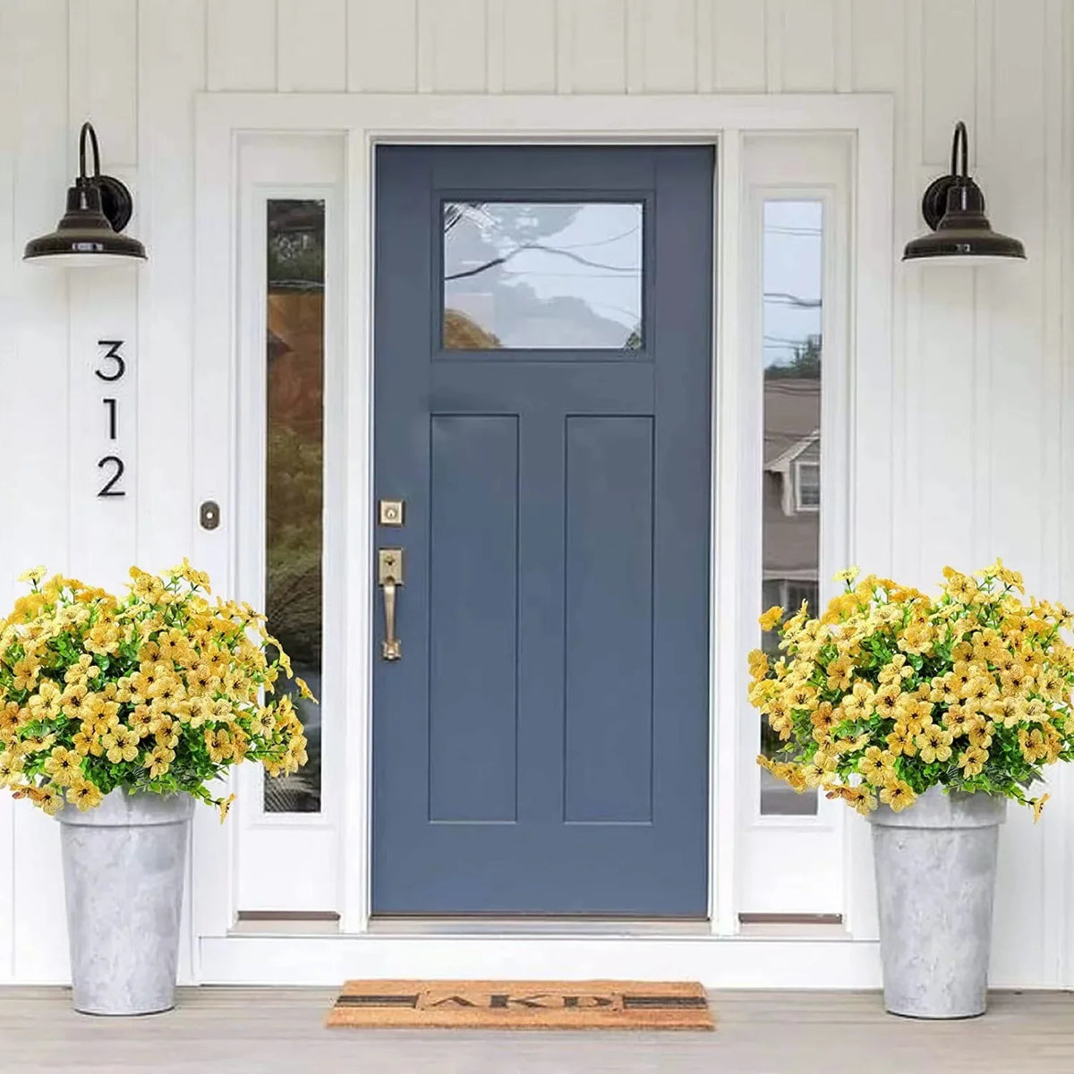 A dark blue door with glass panels flanked by white trim and potted yellow artificial flowers.