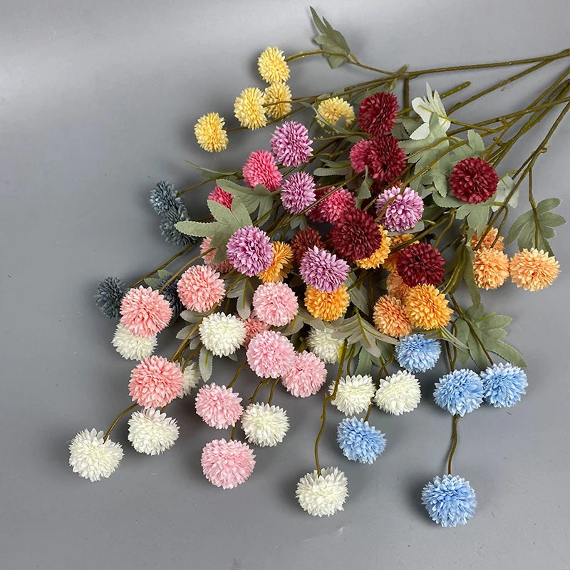 Una ráfaga de flores artificiales de crisantemo y diente de león en tonos rosa, amarillo, rojo y azul.