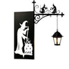 A black silhouette of a witch and cauldron design mounted on a wrought iron bracket with a hanging lantern light.
