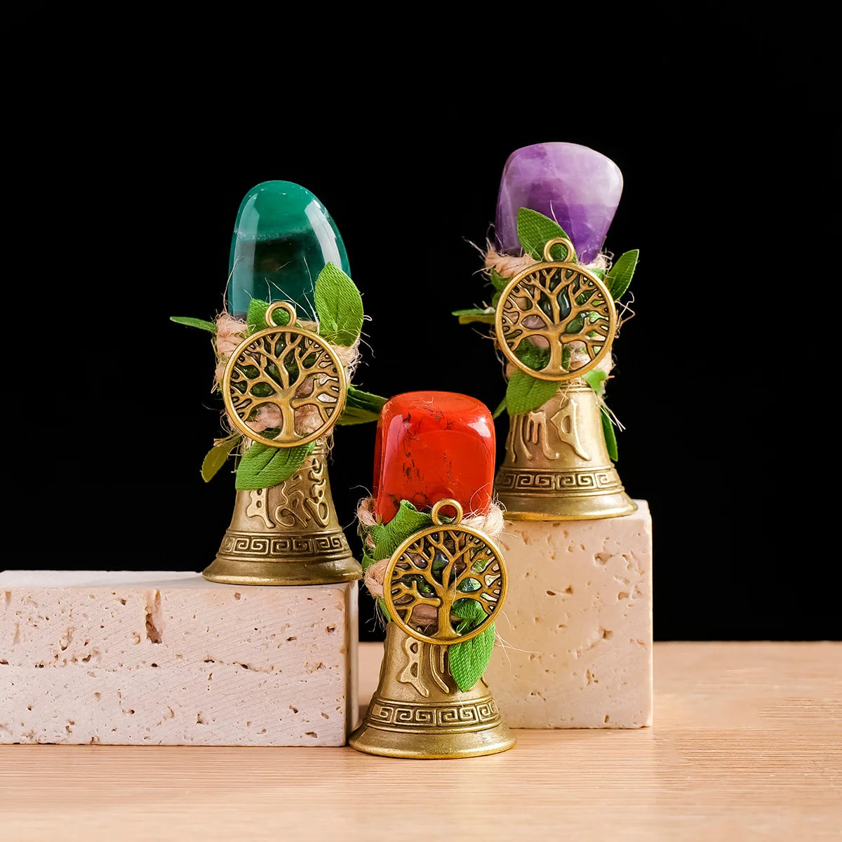 Three natural crystal trees of life chimes in shades of green, purple, and red displayed on light blocks.