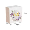 A rectangular, light pink acrylic gift box with a circular floral wreath design on the lid.