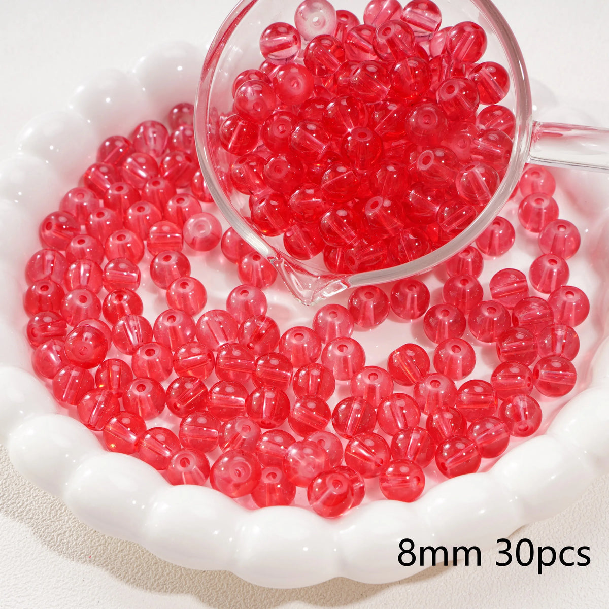 A clear glass dropper shows a pile of bright red round spacer beads for jewelry making