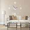 A modern living room wall featuring a white sofa and a frameless acrylic digital wall clock above a glass table.