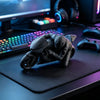 A dark gray 3D printed figurine of a racing motorcycle rider is displayed on a desk next to a keyboard and headphones.